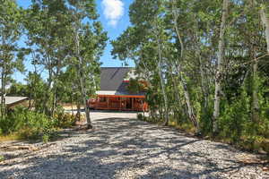 View of property exterior with gravel driveway, a metal roof, and a porch