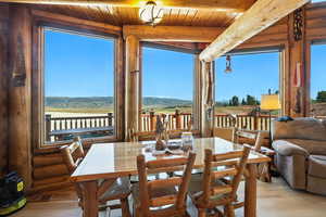 Dining room featuring wood finished floors, a mountain view, beam ceiling, and log walls