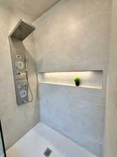 Shower with body sprays, wand, and back lighting in niche