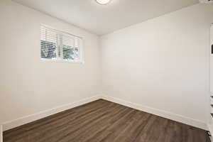 Spare room featuring baseboards and dark wood-style flooring