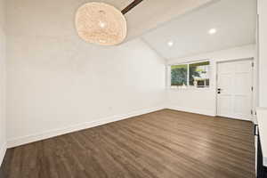 Spare room with vaulted ceiling, dark wood-type flooring, and recessed lighting