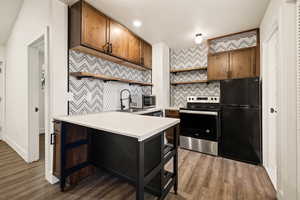 Kitchen with open shelves, light countertops, appliances with stainless steel finishes, decorative backsplash, and dark wood-style floors