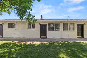 View of front of house featuring a front yard, brick siding, and a patio