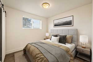 Bedroom featuring a barn door and wood finished floors