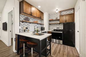 Kitchen with open shelves, tasteful backsplash, appliances with stainless steel finishes, light countertops, and a peninsula