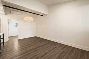 Spare room with dark wood-style floors and an AC wall unit