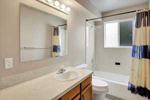Full bath with shower / bath combo with shower curtain, vanity, and light tile patterned floors