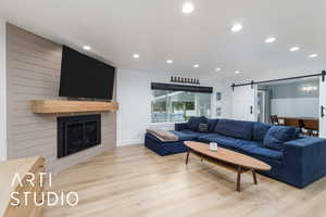 Living area featuring a barn door, recessed lighting, light wood-style floors, and a fireplace