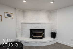 Detailed view of a brick fireplace, carpet floors, and recessed lighting