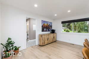 Living area with light wood-type flooring and recessed lighting