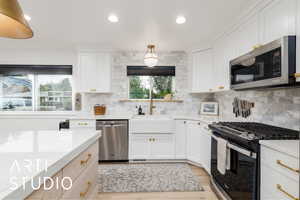 Kitchen featuring stainless steel appliances, recessed lighting, white cabinets, light wood-style floors, and decorative backsplash