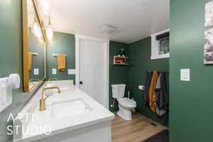 Bathroom featuring a textured ceiling, light wood finished floors, and double vanity