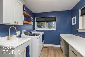 Laundry area with light wood finished floors, cabinet space, and washing machine and clothes dryer