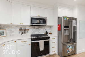 Kitchen featuring stainless steel appliances, white cabinetry, tasteful backsplash, and light wood finished floors