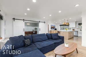 Living room with light wood-type flooring, a barn door, and recessed lighting