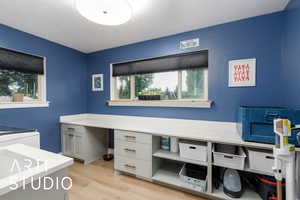 Office with light wood-type flooring and a textured ceiling