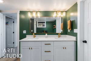 Bathroom featuring double vanity, a textured ceiling, and wood finished floors