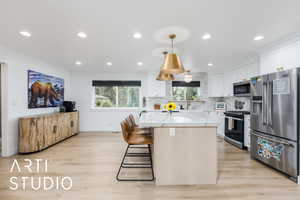 Kitchen with appliances with stainless steel finishes, a kitchen island, recessed lighting, light wood-style floors, and hanging light fixtures