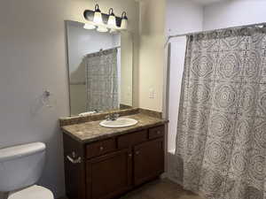 Full bathroom featuring vanity, dark tile patterned floors, and shower / tub combo with curtain