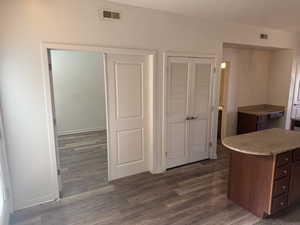 Kitchen featuring dark wood-type flooring, light stone counters, and dark brown cabinetry