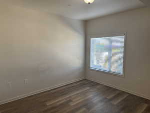 Unfurnished room featuring baseboards and dark wood-type flooring