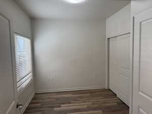 Unfurnished bedroom with dark wood-style flooring, a closet, and a textured ceiling