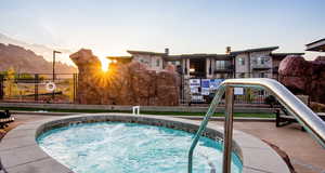 Pool at dusk with a hot tub, a mountain view, a patio, and a swimming pool