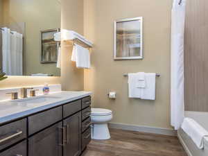 Bathroom featuring dark wood-type flooring, vanity, and shower / bath combo