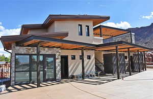 Rear view of property featuring stone siding, stucco siding, a mountain view, and a patio area