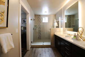 Full bath with dark wood finished floors, a shower stall, and vanity
