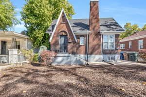 View of front of home featuring brick siding, roof with shingles, and a chimney