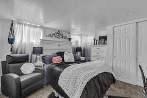 Bedroom featuring carpet flooring, a textured ceiling, and a closet