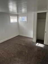 Unfurnished bedroom featuring dark colored carpet, a closet, and a textured ceiling