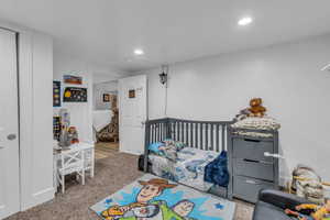 Carpeted bedroom with a nursery area and recessed lighting