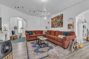 Living room featuring arched walkways, wood finished floors, a textured ceiling, and track lighting