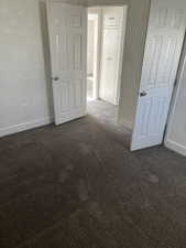 Unfurnished bedroom featuring dark carpet and baseboards