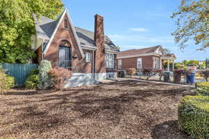 View of front of property with brick siding, a chimney, and a shingled roof