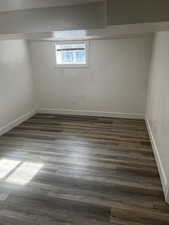 Spare room with baseboards and dark wood-type flooring