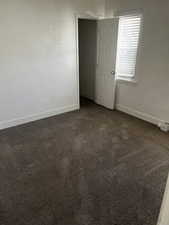 Empty room featuring dark colored carpet and baseboards