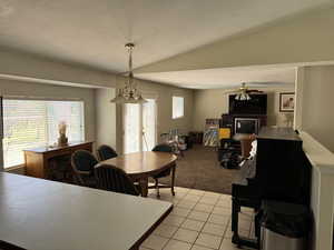 Dining room with a textured ceiling, healthy amount of natural light, lofted ceiling, light tile patterned floors, and light colored carpet