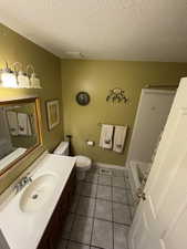 Full bathroom with light tile patterned flooring, a textured ceiling, vanity, and  shower combination