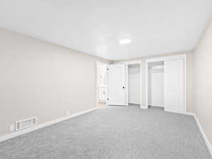 Unfurnished bedroom featuring two closets and light carpet