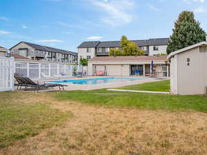 Community pool with a patio area, a storage shed, and a residential view