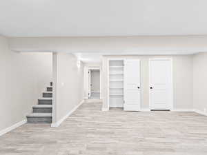 Finished below grade area featuring stairway and light wood-style floors