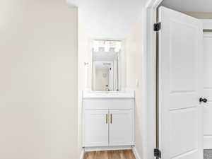 Bathroom with light wood finished floors, vanity, and a textured ceiling