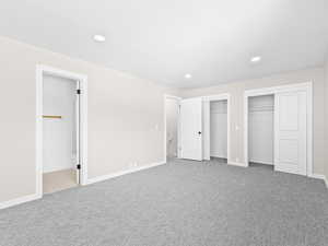 Unfurnished bedroom with multiple closets, light colored carpet, recessed lighting, and connected bathroom