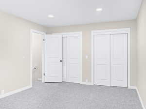 Unfurnished bedroom featuring carpet floors, two closets, and recessed lighting