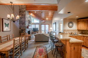 Kitchen featuring a kitchen breakfast bar, a stone fireplace, plenty of natural light, and a wood ceiling with exposed beams.