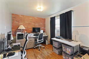 Office space featuring light wood finished floors and brick wall