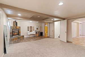 Living room featuring carpet floors, recessed lighting, beamed ceiling, a tiled fireplace, and arched walkways